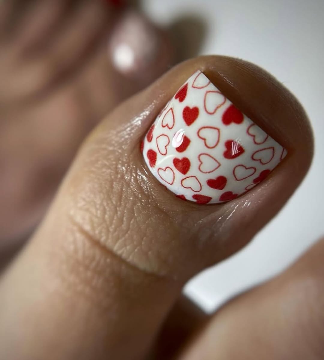 Biały pedicure z drobnymi czerwonymi serduszkami