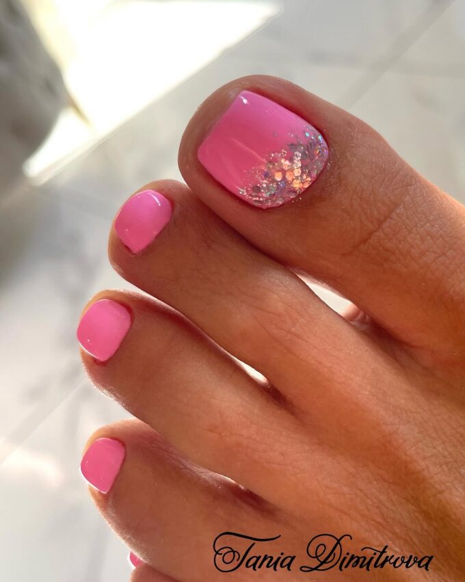 Różowy pedicure z brokatową poświatą na dużym paznokciu