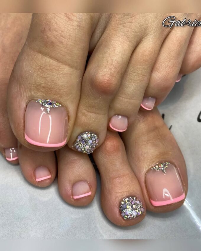 Jasnoróżowy french pedicure z brokatowymi kamieniami na dużych paznokciach